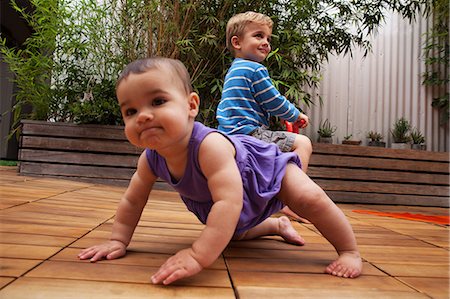 deck gardens - Baby girl crawling on patio, brother in background Stock Photo - Premium Royalty-Free, Code: 614-06896708