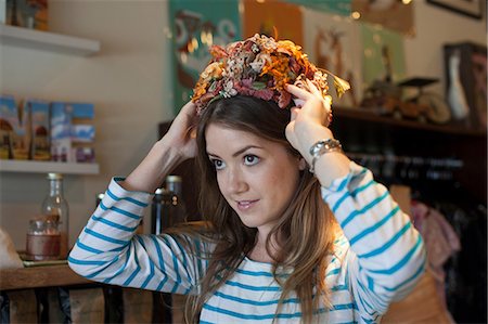 fashion store - Young woman trying on floral hat in vintage shop Stock Photo - Premium Royalty-Free, Code: 614-06896761