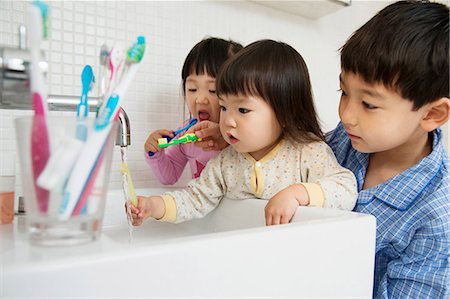 frame with hand - Brother helping sisters to clean teeth Stock Photo - Premium Royalty-Free, Code: 614-06896914