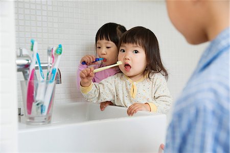 frame with hand - Two girls brushing teeth at bathroom sink Stock Photo - Premium Royalty-Free, Code: 614-06896912