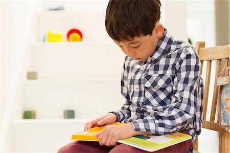 study in a home - Young boy sitting on chair studying game Stock Photo - Premium Royalty-Free, Code: 614-06896929