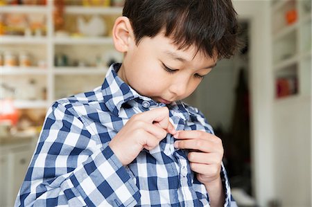 damiers - Close up portrait of young boy fastening shirt buttons Photographie de stock - Premium Libres de Droits, Code: 614-06896935