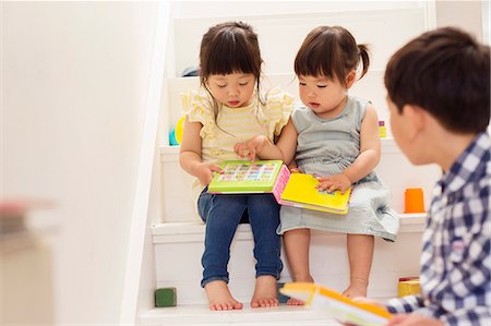 Female toddlers on stairs with game book Fotografie stock - Premium Royalty-Free, Codice: 614-06896931