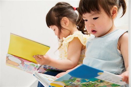 Two young sisters looking at picture books Stock Photo - Premium Royalty-Free, Code: 614-06896932