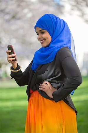 Portrait of young female in park looking at her mobile phone Stock Photo - Premium Royalty-Free, Code: 614-06897042