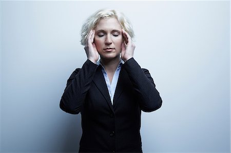 exhausted - Studio portrait of businesswoman with hands on face Stock Photo - Premium Royalty-Free, Code: 614-06897237