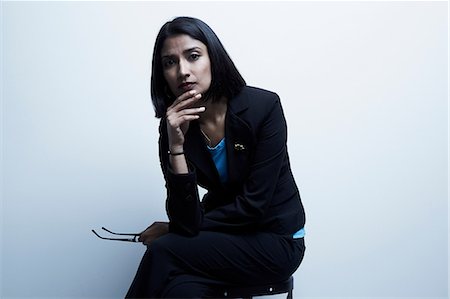 portrait of businesswoman - Studio portrait of businesswoman holding spectacles Stock Photo - Premium Royalty-Free, Code: 614-06897233