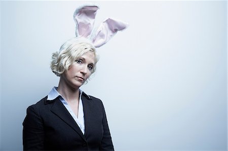 displeased - Studio portrait of blond businesswoman wearing bunny ears Stock Photo - Premium Royalty-Free, Code: 614-06897247