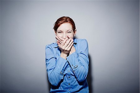 portrait, grey background - Studio portrait of young woman giggling Stock Photo - Premium Royalty-Free, Code: 614-06897266