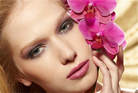 flower head - Close up portrait of young woman holding orchid stem Stock Photo - Premium Royalty-Free, Code: 614-06897316