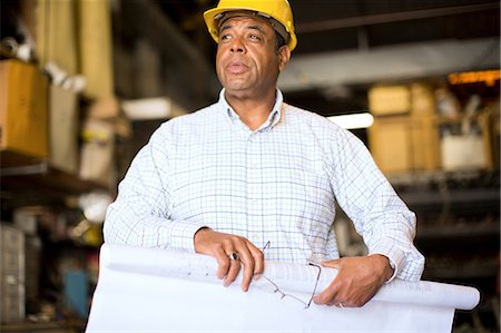 décision - Man in warehouse rolling up blueprint Photographie de stock - Premium Libres de Droits, Code: 614-06897353
