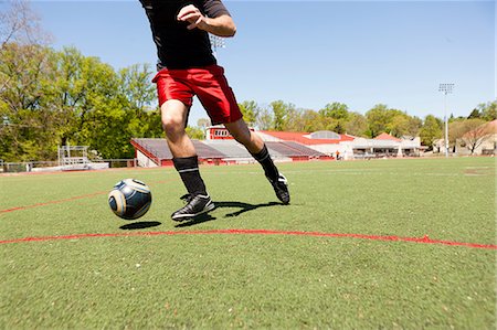 someone playing football kicking the ball - Soccer player running down pitch with ball Stock Photo - Premium Royalty-Free, Code: 614-06897426