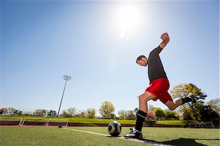 sunlight fun outdoor game - Soccer player taking free kick Stock Photo - Premium Royalty-Free, Code: 614-06897434