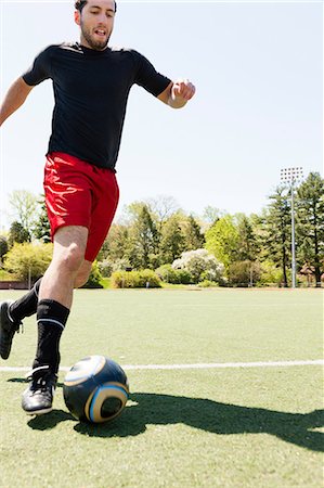 sunlight fun outdoor game - Soccer player running and dribbling ball Stock Photo - Premium Royalty-Free, Code: 614-06897436