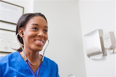 Nurse using stethoscope and smiling Stock Photo - Premium Royalty-Free, Code: 614-06897452