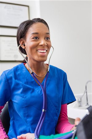 Nurse using stethoscope and smiling Stock Photo - Premium Royalty-Free, Code: 614-06897453