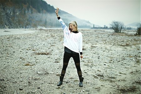 fashion full body woman not male - Woman standing in remote setting making peace sign Stock Photo - Premium Royalty-Free, Code: 614-06897525