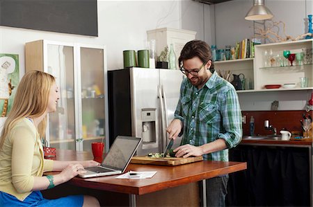 simsearch:614-06897565,k - Woman on laptop computer, man chopping vegetables Stock Photo - Premium Royalty-Free, Code: 614-06897561