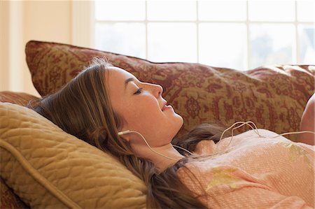 escucha - Teenage girl lying on sofa with earphones Foto de stock - Sin royalties Premium, Código: 614-06897607