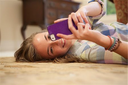 Teenage girl lying on floor with cell phone Stock Photo - Premium Royalty-Free, Code: 614-06897614