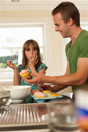 spreading (applying food) - Young girl with older brother icing cupcakes Foto de stock - Sin royalties Premium, Código: 614-06897668