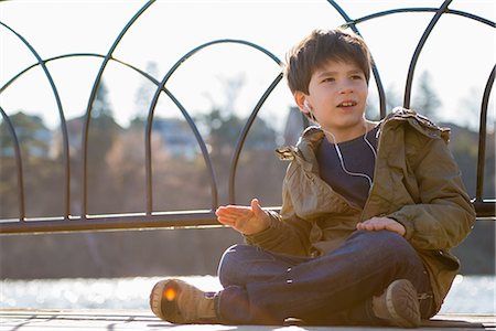 Boy sitting cross legged wearing earphones Stock Photo - Premium Royalty-Free, Code: 614-06897705