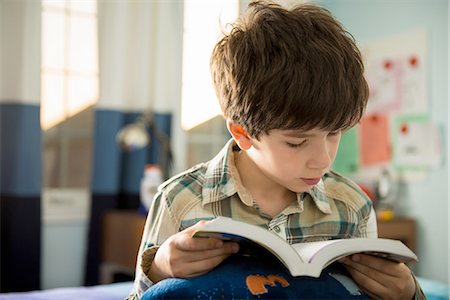 Boy sitting on bed reading book Photographie de stock - Premium Libres de Droits, Code: 614-06897715