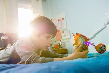 Boy lying on bed with toy Stock Photo - Premium Royalty-Free, Code: 614-06897711