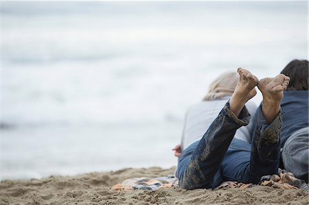 simsearch:614-06897719,k - Mature couple lying on beach looking at sea Fotografie stock - Premium Royalty-Free, Codice: 614-06897734