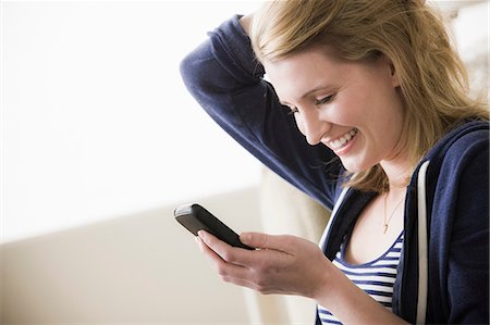 sms - Young woman with cell phone and hand in hair Stock Photo - Premium Royalty-Free, Code: 614-06897757