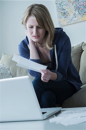 Worried young woman holding bills Stock Photo - Premium Royalty-Free, Code: 614-06897769