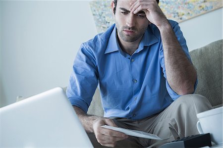 Worried man with hand on head holding bills Fotografie stock - Premium Royalty-Free, Codice: 614-06897773