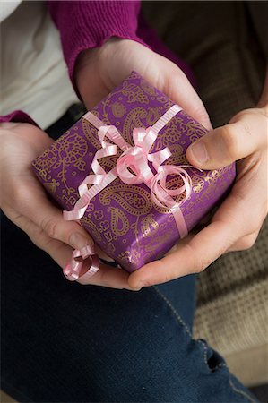 Two people holding gift box with pink ribbon Stock Photo - Premium Royalty-Free, Code: 614-06897781