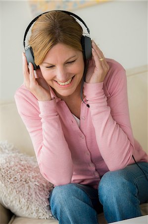 fone de ouvido - Mature woman wearing headphones, smiling Foto de stock - Royalty Free Premium, Número: 614-06897828