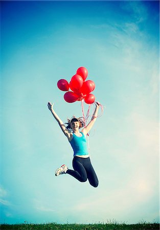 Teenage girl jumping in mid air holding red balloons Stock Photo - Premium Royalty-Free, Code: 614-06897846