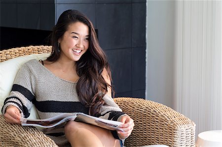 simsearch:614-06897933,k - Portrait of young woman sitting on armchair with magazine Foto de stock - Royalty Free Premium, Número: 614-06897933