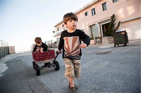 Boy pulling brother along in cart Stock Photo - Premium Royalty-Free, Code: 614-06898002