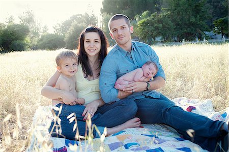 portrait of woman and her boy smiling - Parents with son and baby daughter on blanket in field Stock Photo - Premium Royalty-Free, Code: 614-06898015