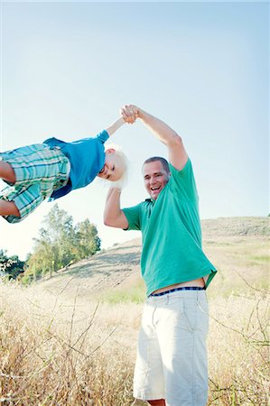 Man swinging son in field Stock Photo - Premium Royalty-Free, Code: 614-06898024