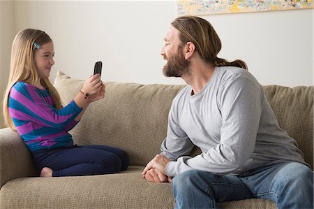 family relaxing living room - Daughter photographing father with smartphone Stock Photo - Premium Royalty-Free, Code: 614-06898280