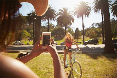 palm tree - Woman photographing friend on bicycle Stock Photo - Premium Royalty-Free, Code: 614-06898329