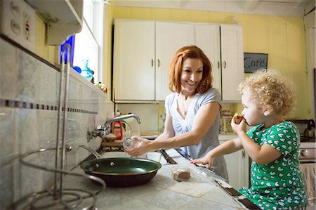 saucepan - Mother at sink smiling at child Stock Photo - Premium Royalty-Free, Code: 614-06898428
