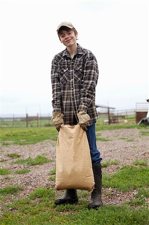 Boy carrying sack of feed Stock Photo - Premium Royalty-Free, Code: 614-06898462
