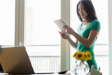 Woman holding digital tablet looking at laptop Foto de stock - Sin royalties Premium, Código: 614-06898474