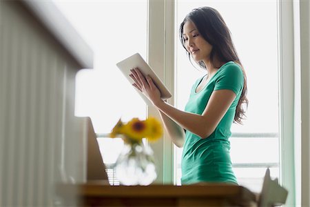 Woman holding up and using digital tablet Stock Photo - Premium Royalty-Free, Code: 614-06898473