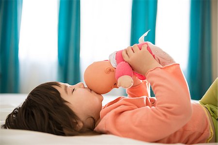 Girl kissing dolly in bedroom Stock Photo - Premium Royalty-Free, Code: 614-06974045