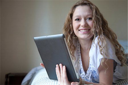 Teenager on bed, reading digital tablet Stock Photo - Premium Royalty-Free, Code: 614-06974308