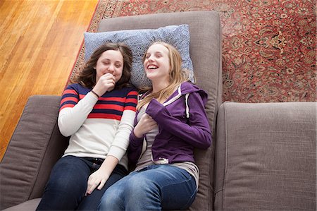 Girls lying on sofa giggling Stock Photo - Premium Royalty-Free, Code: 614-06974327