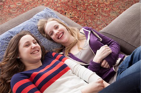 secretive - Girls lying on sofa giggling Stock Photo - Premium Royalty-Free, Code: 614-06974328