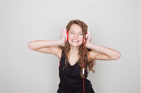 Girl wearing headphones with hands over ears Stock Photo - Premium Royalty-Free, Code: 614-06974370